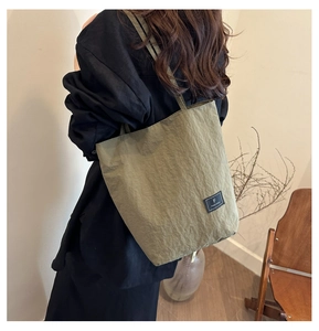 Detail of olive green pleated tote bag showing the texture and brand label on shoulder