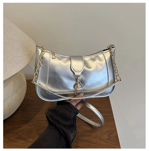 Detail of silver crescent shoulder bag with golden chain strap and metallic texture