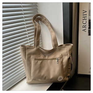 Detail of minimalist beige canvas tote bag with good luck patch and front zipper pocket
