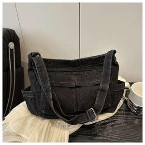 Detail of black denim crossbody bag with multiple utility pockets and adjustable strap