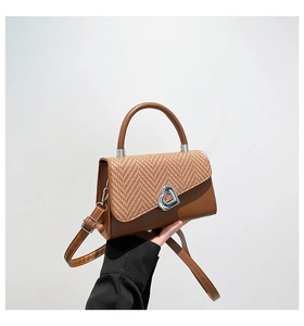 Detail of brown crossbody bag with woven texture lid and silver heart shaped metal lock