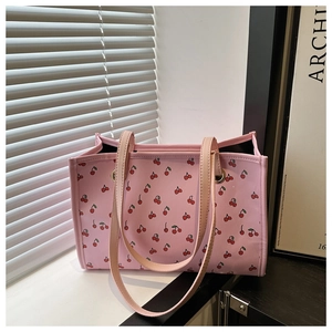 Dettaglio della borsa tote in tela rosa con stampa di ciliegie rosse e manici in tessuto