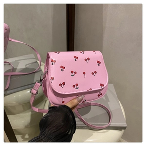 Detail shot of a pink mini crossbody bag featuring sweet red cherry prints and PU leather