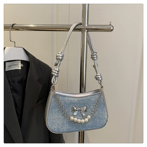 Detail of light blue denim shoulder bag with silver butterfly and pearl chain ornaments