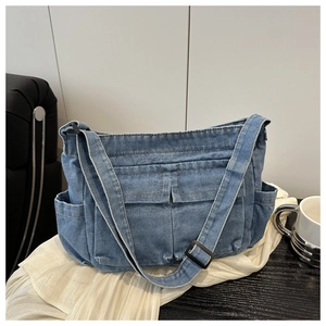 Detail of blue denim shoulder bag with multiple utility pockets and adjustable strap