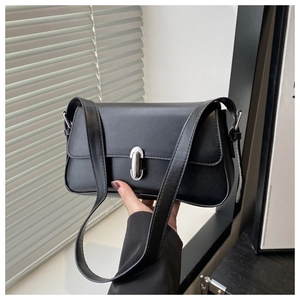 Detail of minimalist black underarm bag featuring a silver metal rotating clasp closure