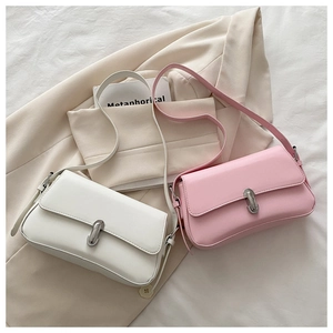 Detail of white and pink PU leather crossbody bags with silver metal buckle on beige fabric