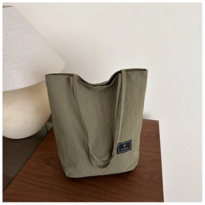 Detailed close-up of dark olive green tote bag fabric texture with black logo label
