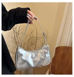 Macro detail of the silver metallic crinkled leather texture and adjustable shoulder strap