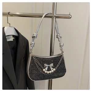Close-up of black sequined shoulder bag with pearl accents and silver butterfly chain detail