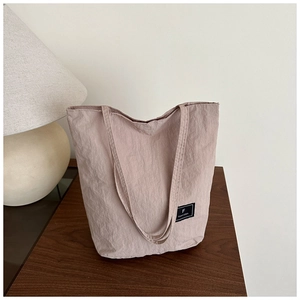 Detail of grey-pink canvas tote bag featuring FANVISSA fabric label on wooden table