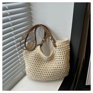 Gros plan du sac fourre-tout tissé beige ajouré avec anses en cuir marron près d'une fenêtre