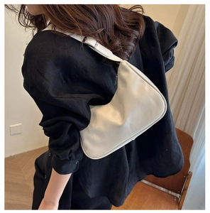 Detail of white PU leather crescent underarm bag with silver buckle worn by a model