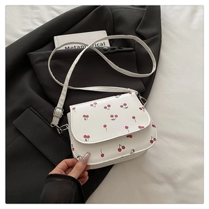 Detail view of white square crossbody bag with red cherry print and silver hardware