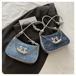 Detail shot of denim crescent bags with pearl butterfly accents and silver chain decor