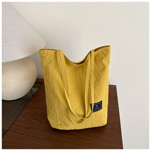 Close-up of ginger yellow nylon tote bag on wooden table with elegant interior lighting