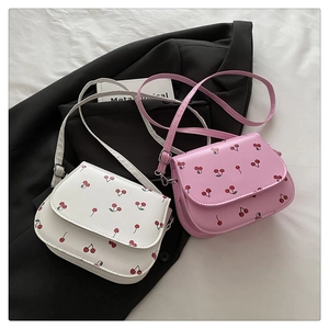 Detail shot of mini crossbody bags in white and pink with red cherry print patterns