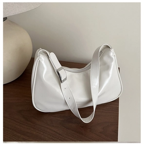 Macro view of white glossy patent leather surface and adjustable silver buckle on hobo bag
