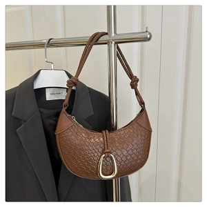 Détail du sac hobo marron tressé avec boucle fer à cheval dorée sur un cintre