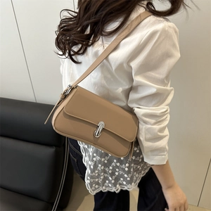 Beige PU leather crossbody bag with silver buckle worn by a model in minimalist style