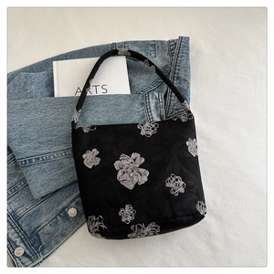 Detail der minimalistischen schwarzen Stofftasche mit Blumenmuster auf Jeans und Stoff