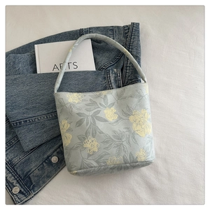 Detail der hellblauen Beuteltasche mit gelbem Blumenmuster und Tragegriff