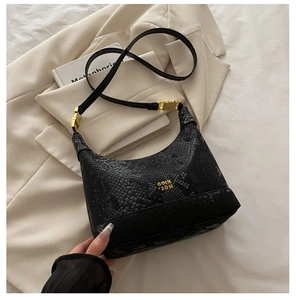 Detail of black snake-embossed hobo bag with gold logo and adjustable strap