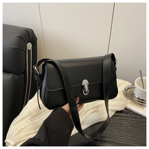 Detail of minimalist black faux leather shoulder bag with silver turn-lock and adjustable strap