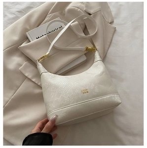 Close-up of beige snake-textured shoulder bag with gold buckle and brand logo
