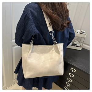 Detail of cream faux leather tote bag with geometric stitching and metal chain strap
