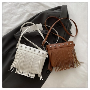 Detail shot of mini fringe crossbody bag with metal studs on soft PU leather surface