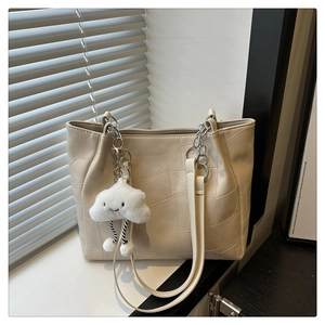 Detail of beige tote bag featuring quilted patchwork texture and cloud charm