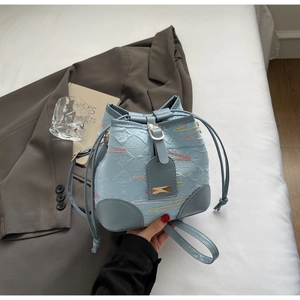 Close-up of sky blue drawstring bucket bag with textured diamond pattern and colorful accents
