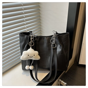 Detail of black woven leather tote bag with chain strap and cute cloud charm pendant