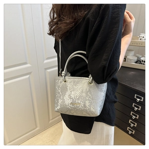 Detail view of silver snake-pattern shoulder bag with gold hardware and fashion text