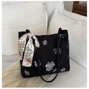 Détail d'un cabas en toile noire avec motif floral blanc et foulard décoratif en soie