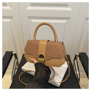 Detail of a chic handbag with brown herringbone flap and golden metal clasp closure