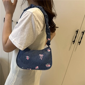 Denim hobo bag with pink rose embroidery and pleated strap on a female model