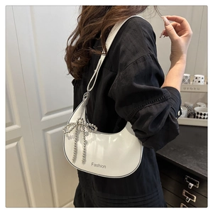 Détail du sac hobo blanc avec breloque nœud en perles et logo sur la bandoulière