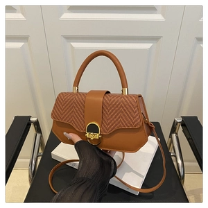 Detail of caramel leather and chevron weave handbag with gold ring buckle closure