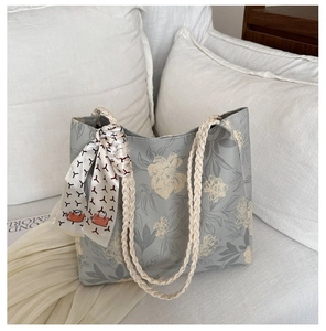 Gros plan du sac cabas floral bleu clair avec poignées tressées et détail foulard soie