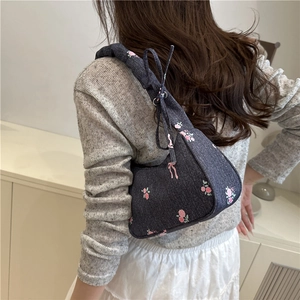 Floral print denim shoulder bag with pink bows shown on model in cozy home setting