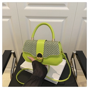 Detail view of lime green crossbody bag featuring a woven black and white flap and metal lock