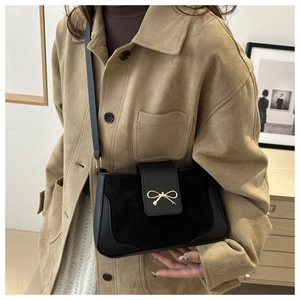 Detail of elegant gold bow-knot metal buckle on a black leather minimalist crossbody bag