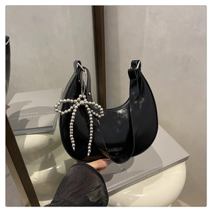 Détail du sac croissant noir avec finition brillante et breloque papillon argentée perlée