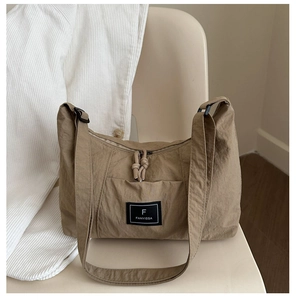 Detail view of khaki nylon crescent bag with corded zipper and brand logo patch