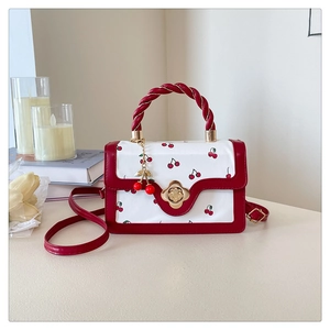 Detail of red and white cherry print bag with gold flower lock and pendant