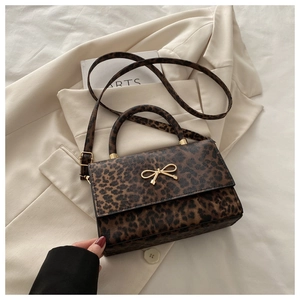 Gros plan du sac léopard avec fermoir nœud doré sur un blazer beige chic