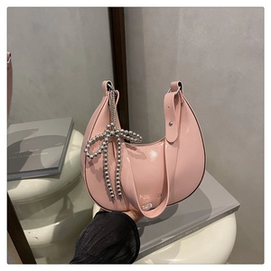 Détail du sac hobo rose en demi-lune avec nœud en perles argentées et sangle mode