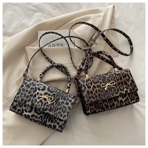 Détail de sacs à bandoulière léopard avec boucle en nœud doré sur un blazer beige